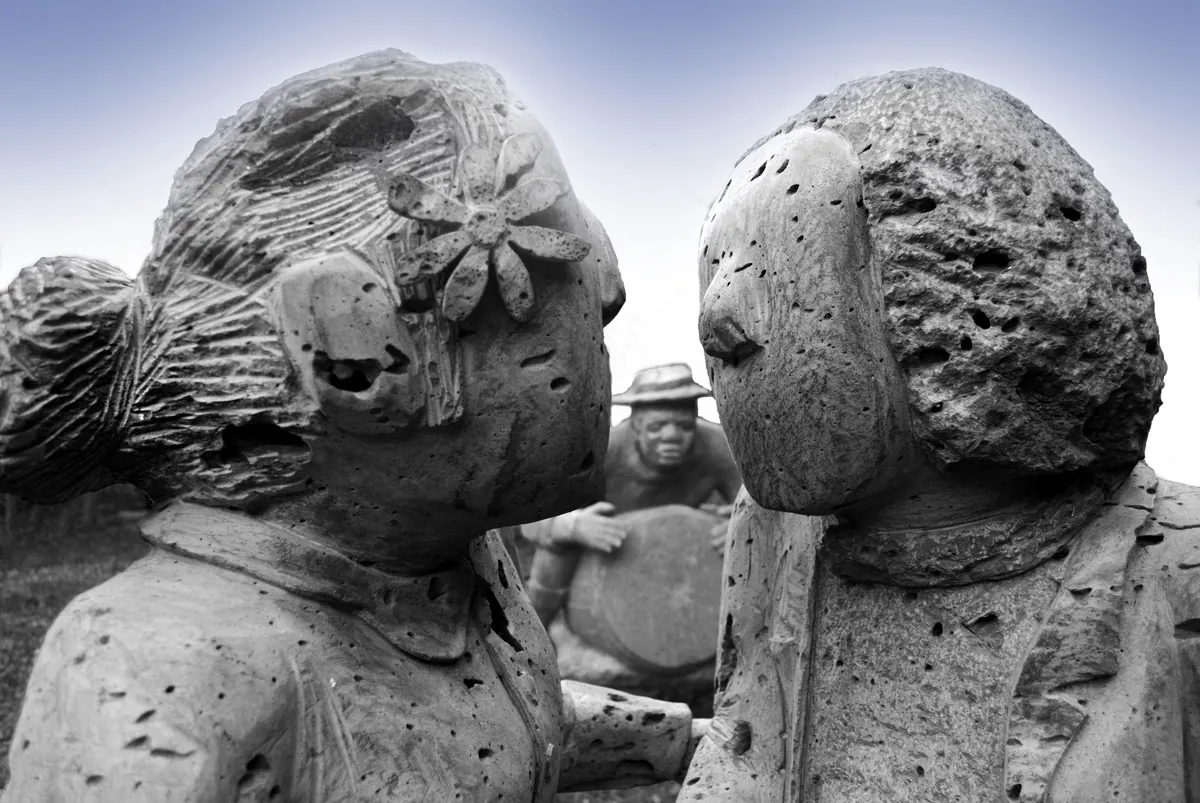 Sculpture en basalte de Marco Ah-Kiem représentant deux enfants dansant le maloya devant un joueur de roulèr